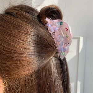 Détail d'une pince à cheveux rose translucide avec motifs de fleurs en strass sur cheveux
