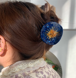 Detail of blue acetate sun hair claw clip worn on a bun hairstyle with natural sunlight