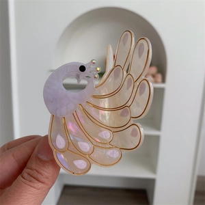 Detail of elegant acetate peacock hair claw clip with pearlescent pink gradient and gold lining