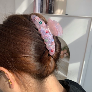 Détail d'une pince à cheveux en acrylique rose avec motifs de fleurs en strass colorés