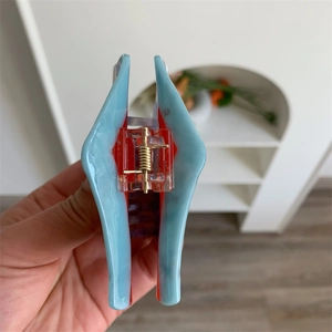 Dettaglio di una grande clip per capelli in acetato con motivo marmo blu e rosso