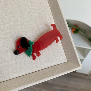 Dettaglio di un fermaglio per capelli a forma di bassotto rosso in acetato lucido