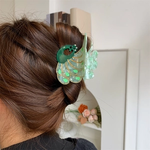Detailed side view of peacock hair claw clip with emerald green acetate and crystal accents