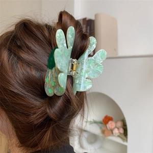 Detail of peacock-shaped green marble hair claw clip on brunette hair with gold edges