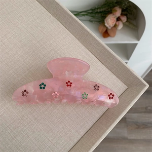 Détail de la pince à cheveux rose translucide ornée de fleurs en strass colorés