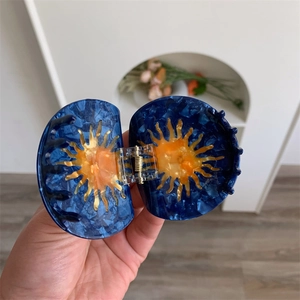 Detail of blue marble cellulose acetate hair claw with orange sunburst pattern