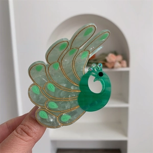 Detail view of peacock hair claw clip with emerald marble texture and golden line accents