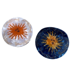 Artistic sun-shaped acetate hair claw clips with celestial patterns in white and navy blue