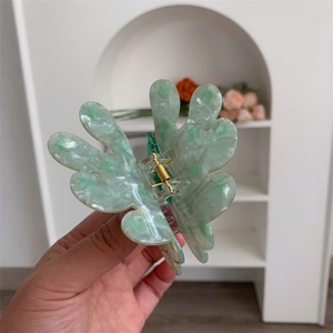 Detailed close-up of peacock style hair claw clip with green marble acetate texture