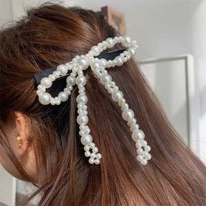 Vista dettagliata di un fermaglio per capelli a fiocco con perle su capelli castani