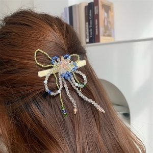Détail d'une pince à cheveux papillon en perles faite main portée sur cheveux longs