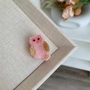 Detalle de pinza para el pelo de búho rosa en acetato con gafas de corazón brillantes