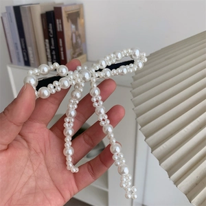 Fermaglio per capelli fatto a mano con perle bianche a forma di fiocco su sfondo minimalista