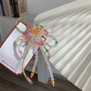 Détail de la pince à cheveux fleurie en perles avec cristaux colorés et longs glands
