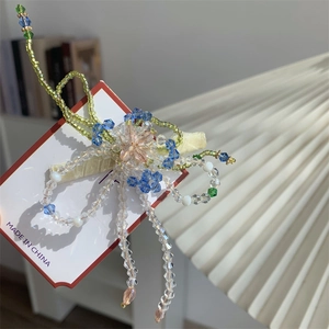 Détail d'une pince à cheveux florale faite main avec perles en cristal et longs pompons