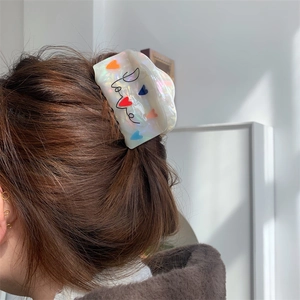 Detailopname van de haarklem van acetaat met gekleurde hartjes en Love tekst erop