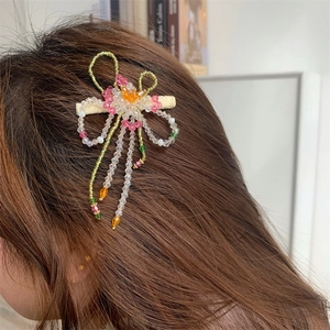 Gros plan d'une pince à cheveux florale en perles et cristaux roses sur cheveux sombres