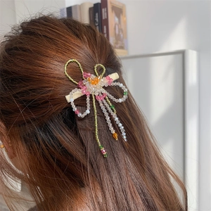 Détail d'une pince à cheveux à fleurs perlées à la main avec pompon coloré sur modèle