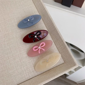 Detail view of oval acetate hair clips with bow ornaments and France Handmade text