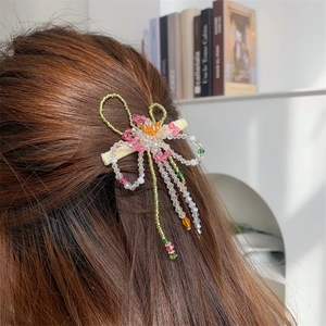 Détail d'une pince à cheveux fleurs en perles de cristal avec pampille sur cheveux bruns