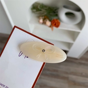 Close-up of cream acetate hair clip featuring embossed bow detail and France Handmade text