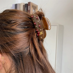 Nahaufnahme der Haarspange mit Herzmuster und goldener Schleife im braunen Haar