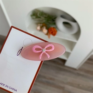 Detailed view of pink acetate hair clip with 3D bow and sparkling central rhinestone
