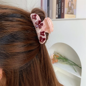 Detailansicht einer Haarklammer mit rosa Marmor-Effekt und roten Blumen-Dekoren