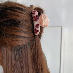 Nahaufnahme einer Blumen-Haarklammer mit rosa Marmor-Textur auf braunem Haar