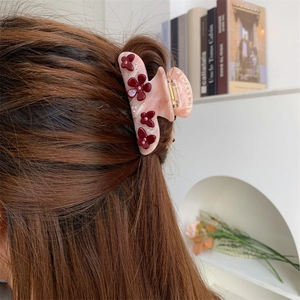 Detailaufnahme einer hellrosa Acetat-Haarklammer mit Blumen-Design in einer Frisur