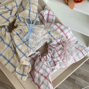 Détail de chouchous à carreaux avec bordure en dentelle et nœuds en jaune et violet