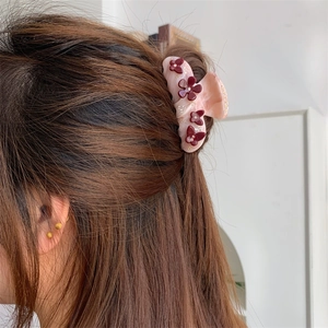 Detail von rosa Blumen-Haarklammer mit roten Blütenblättern und Strass im Haar