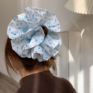 Chouchou géant bleu à fleurs sur modèle, vue de dos dans un décor intérieur minimaliste