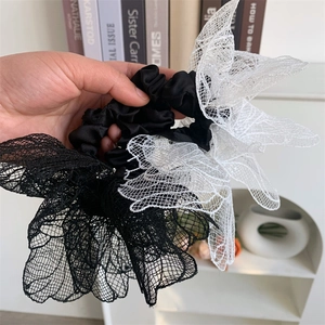 Close-up of oversized mesh lace flower hair ties in black and beige layered fabric
