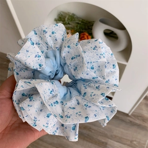 Détail du chouchou surdimensionné bleu clair à fleurs avec texture plissée et tissu doux
