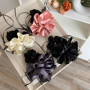 Détail de quatre chouchous en satin colorés avec de longs rubans noirs sur un plateau