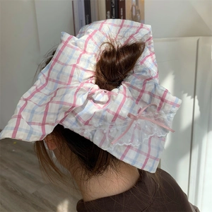 Détail d'un chouchou à carreaux rose et bleu avec dentelle blanche et nœud rose