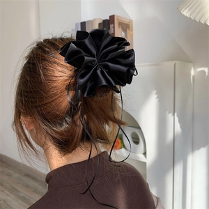 Vue arrière d'un modèle portant un chouchou fleur en satin noir brillant à rubans