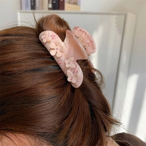 Rosa Haarklammer mit Blumen- und Schmetterlingsdesign und Strass auf braunem Haar