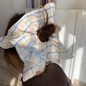 Détail d'un chouchou à carreaux bleu et jaune avec dentelle blanche et ruban