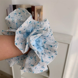 Gros plan d'un grand chouchou à fleurs bleues avec bords plissés au poignet