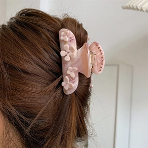 Detailansicht der rosa Haarklammer aus Acetat mit Blumenrelief und glänzenden Strasssteinen