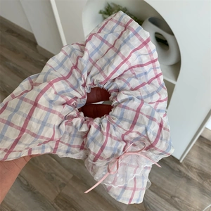 Gros plan d'un chouchou à carreaux rose et bleu avec dentelle blanche et nœud rose