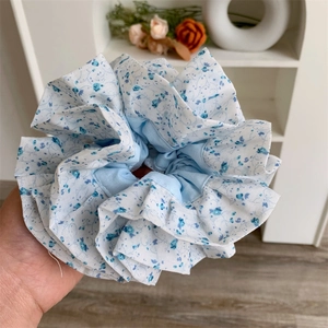 Gros plan d'un grand chouchou à fleurs bleues avec des plis et une texture douce