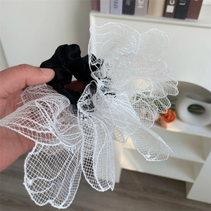 Detail of large white lace flower hair tie with black satin elastic band macro shot