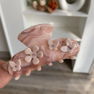 Detailansicht der Haarspange aus rosa Acetat mit weißen 3D-Blumen und Schmetterlings-Akzenten