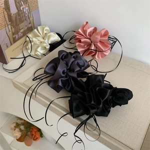 Détail de chouchous en satin soyeux avec de longs rubans en crème, rose, gris et noir