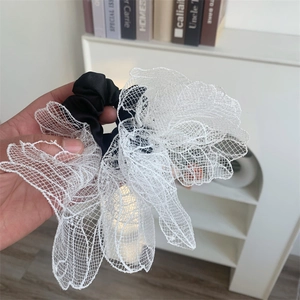 Close-up of a large white lace flower hair scrunchie with black elastic satin band detail