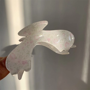 Detailed view of translucent floral acrylic claw clip with glitter and flower pattern