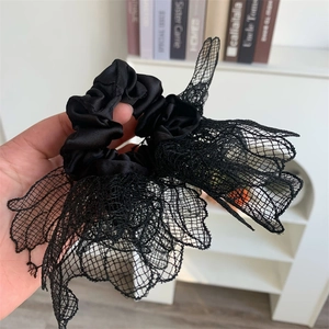 Detail of black lace scrunchie showing fine mesh texture and layered floral design edges